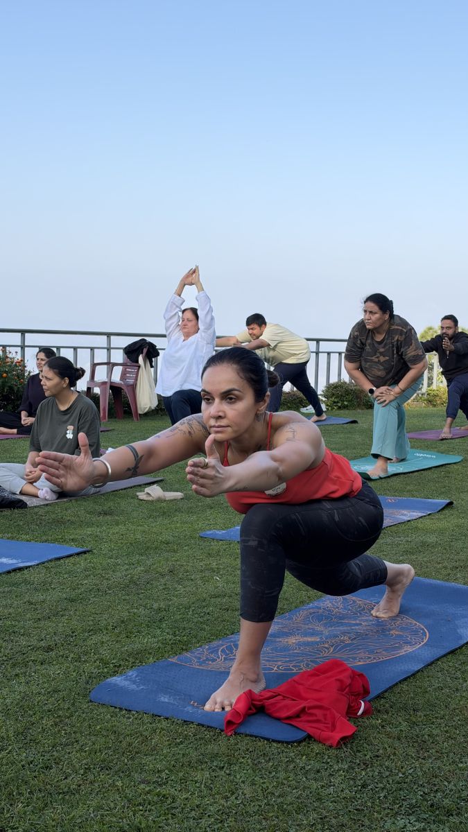 A figure in a yoga pose on a hilltop at sunrise