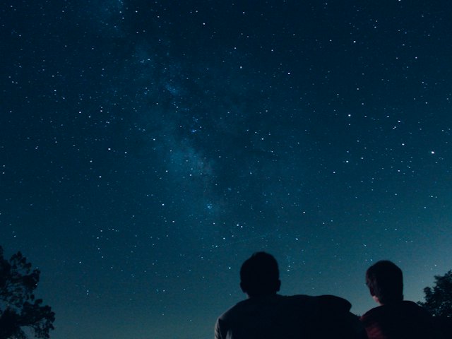 Two people watching a sky full of stars